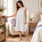 Model beside a bedroom bookcase wearing the Lamros lilac sleeveless floral nightdress