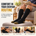 Men's black and mustard-gold over-the-calf socks worn while relaxing and reading at home